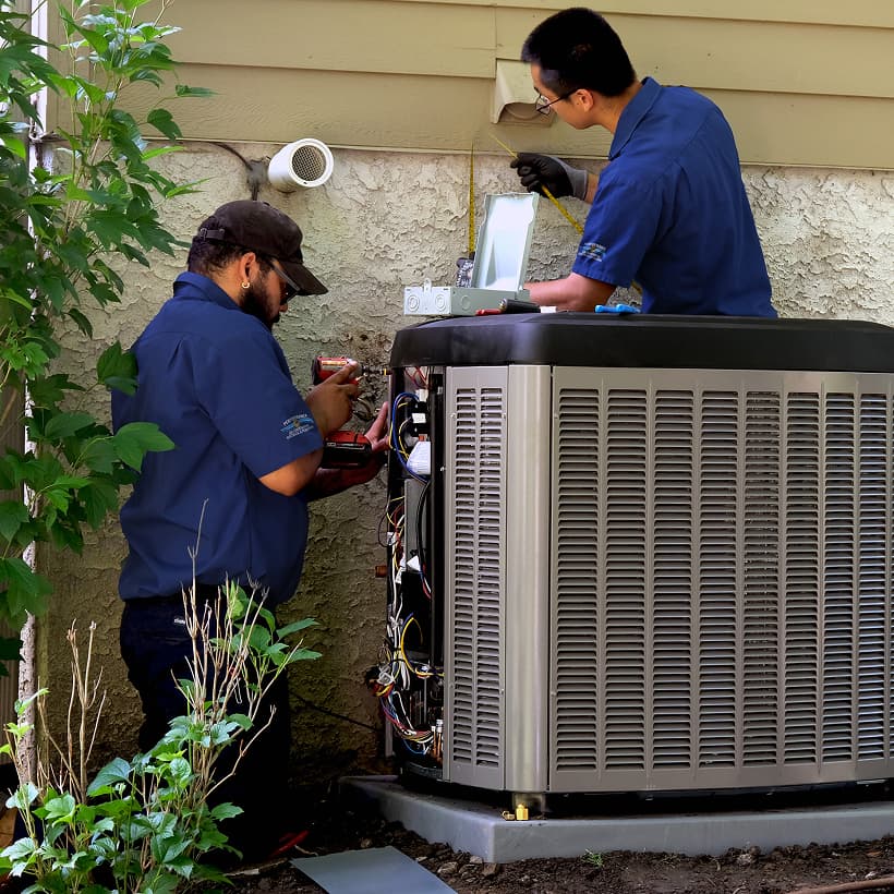 Two Performance HVAC technicians installing a brand-new residential outdoor air conditioning condenser unit during a home AC replacement service.
