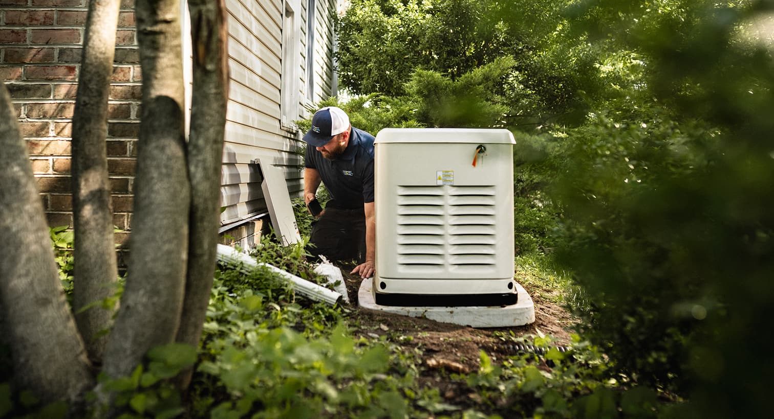 A professional Performance technician inspects a large, beige whole-home standby generator installed on a concrete pad outside a residential house.