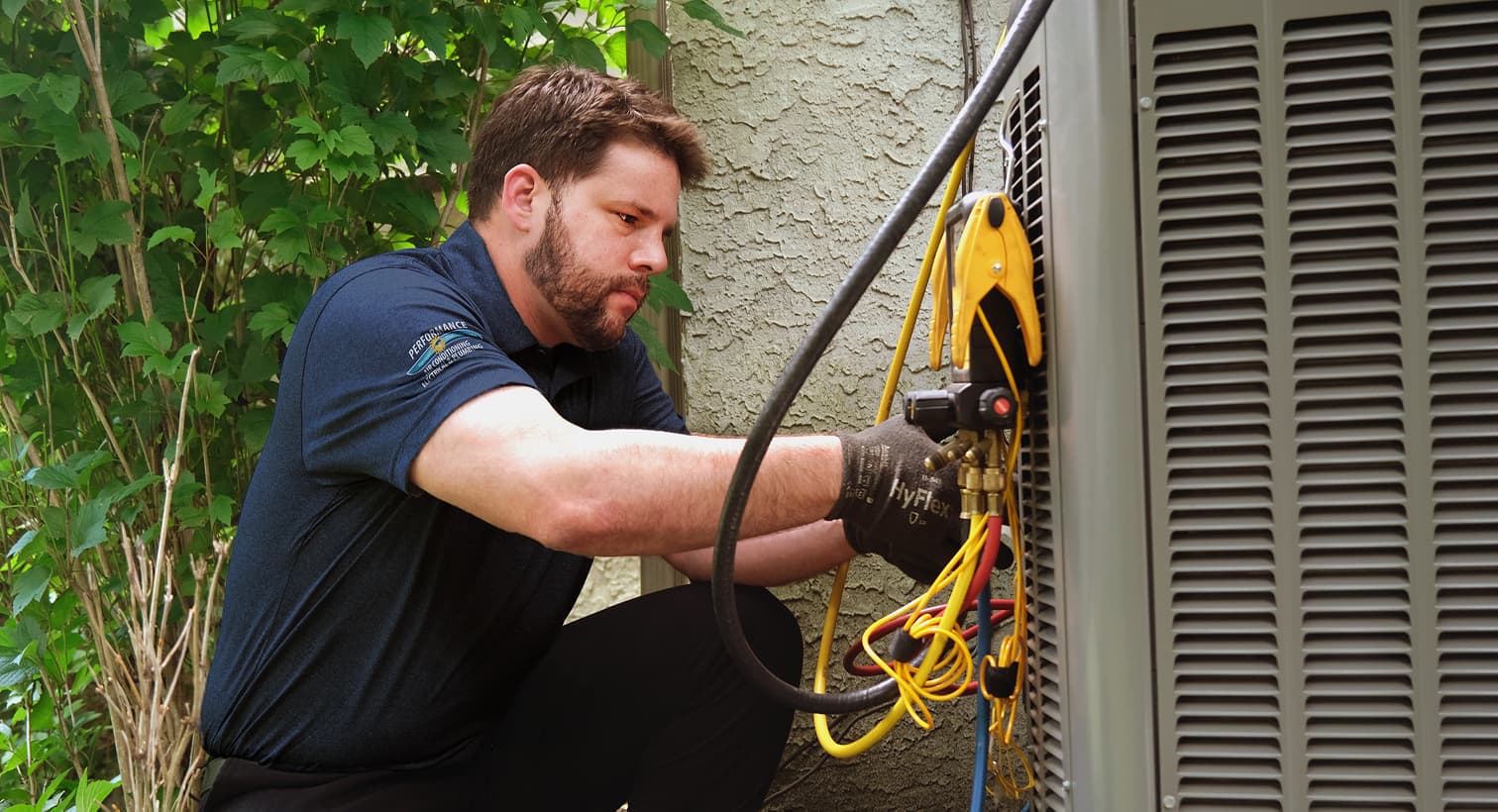 A professional Performance HVAC technician inspecting an outdoor central air conditioning unit to provide residential AC repair and diagnostic services.